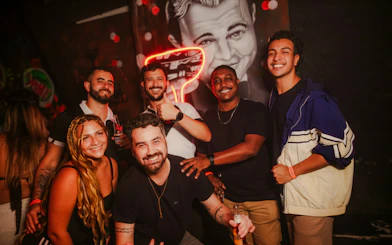 Group enjoying nightlife at Substation Club Rio, Rio de Janeiro, with neon art in the background.