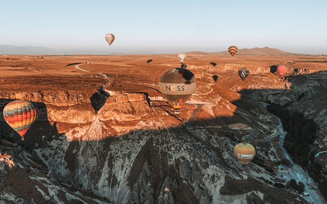 Hot air balloons floating over Soganli Valley, Cappadocia, during sunrise.