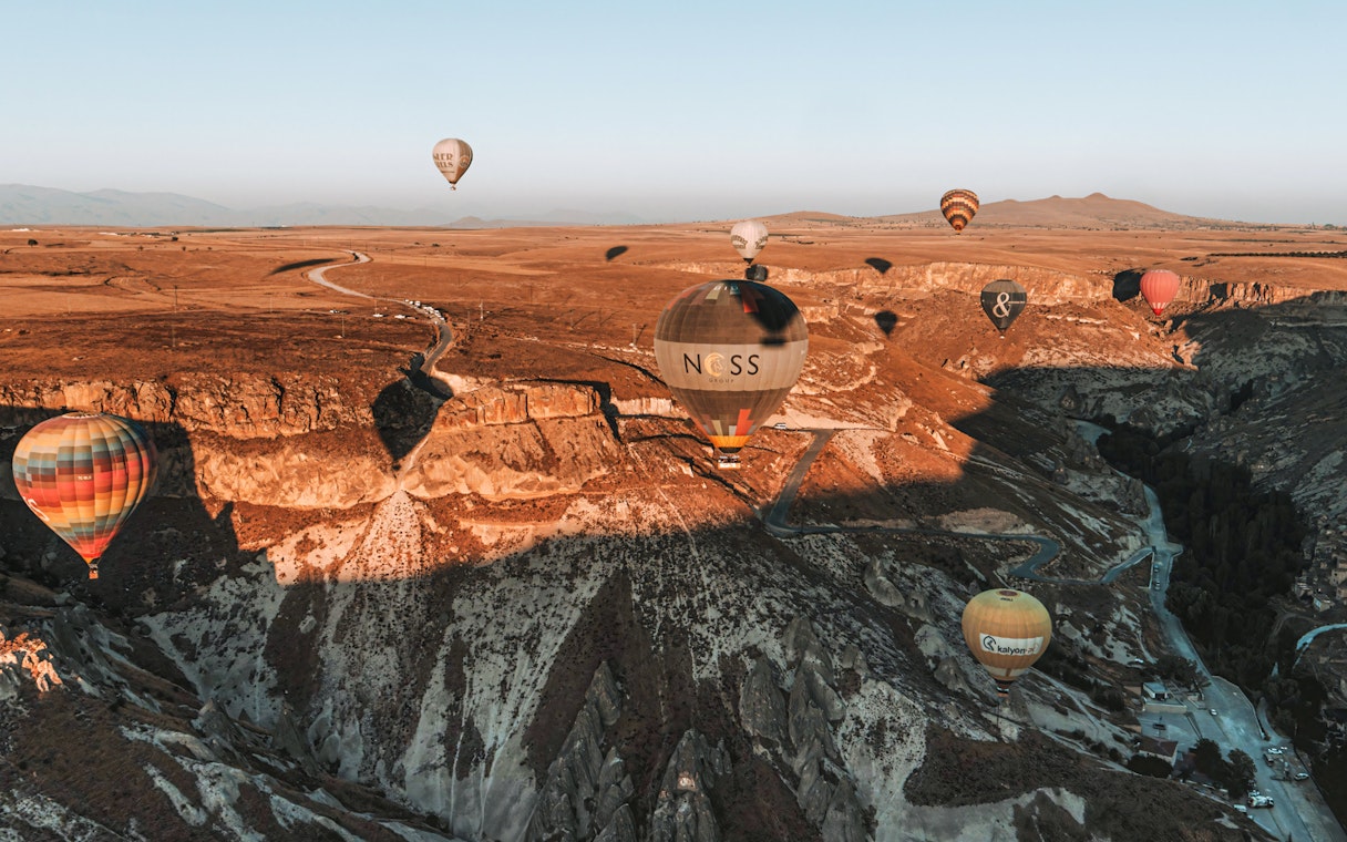 Hot air balloons floating over Soganli Valley, Cappadocia, during sunrise.