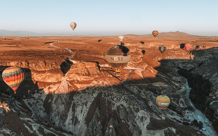 Hot air balloons floating over Soganli Valley, Cappadocia, during sunrise.