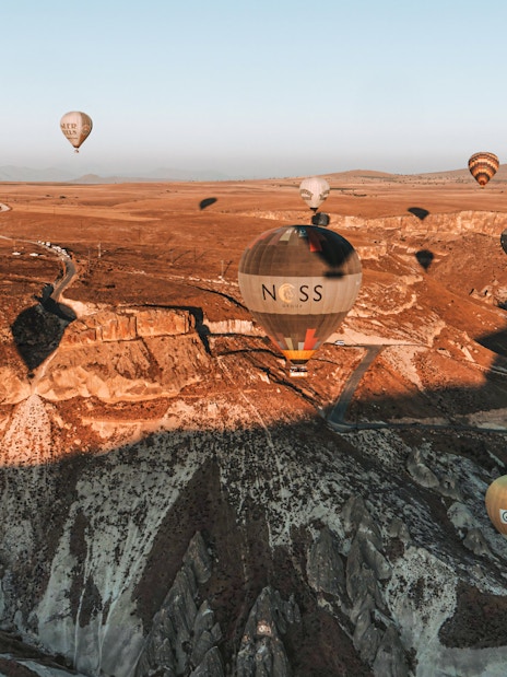 Hot air balloons floating over Soganli Valley, Cappadocia, during sunrise.