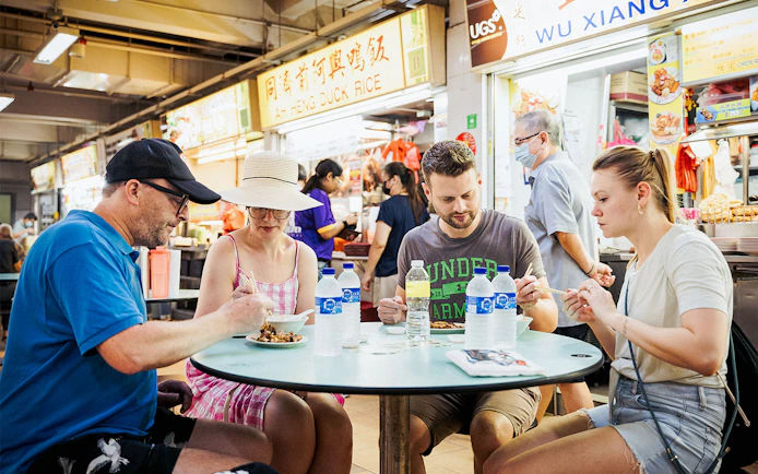 Group enjoying local dishes at a hawker center during a guided food tour.