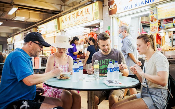 Group enjoying local dishes at a hawker center during a guided food tour.