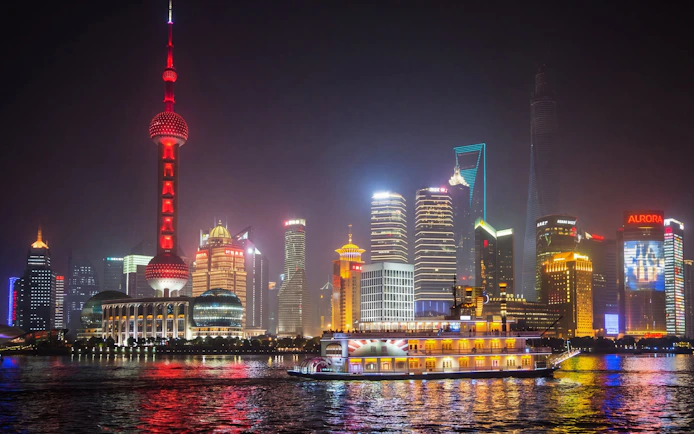 Huangpu River cruise with Shanghai skyline and Oriental Pearl Tower at night.