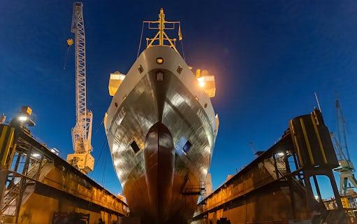 Cruise ship docked at Grand Harbor under evening lights.