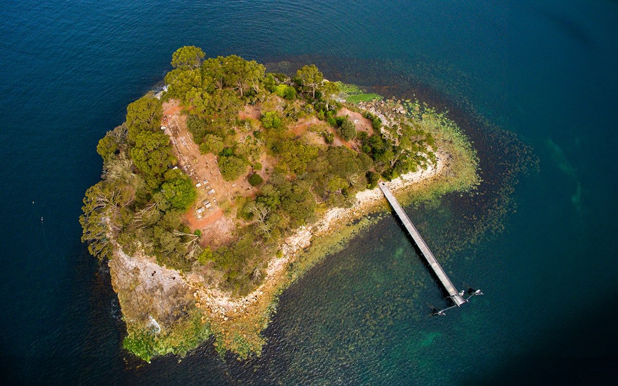 Aerial view of Isle of the Dead at Port Arthur Historic Site, showing dense trees and a long pier.