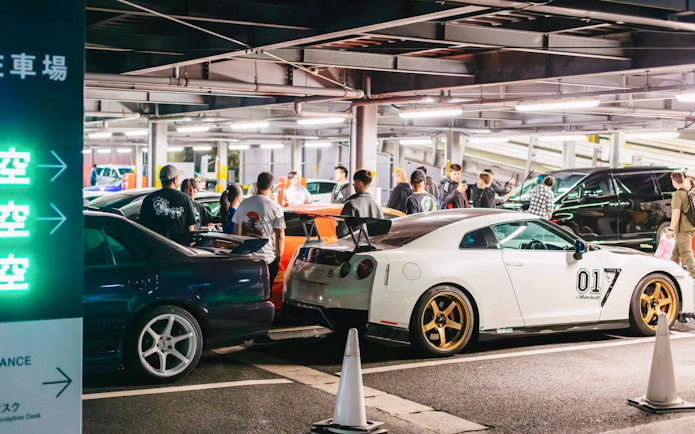 Tokyo parking garage with sports cars and people during Fast & Furious Tokyo Drift III Experience.