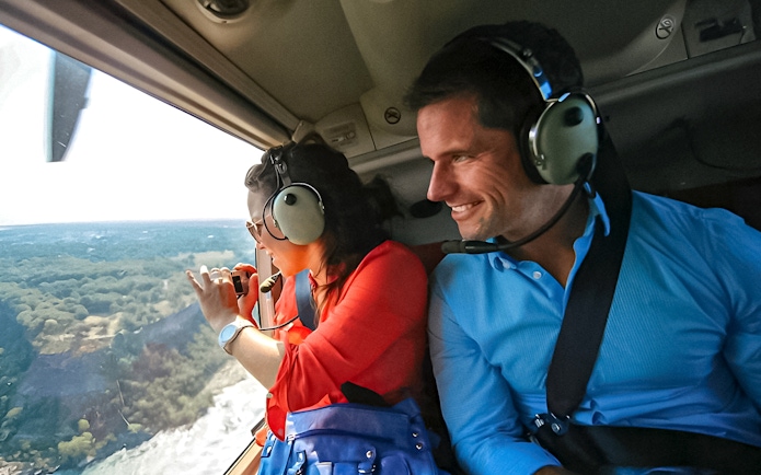 Helicopter passengers view Niagara Falls from above, capturing the scenic landscape.