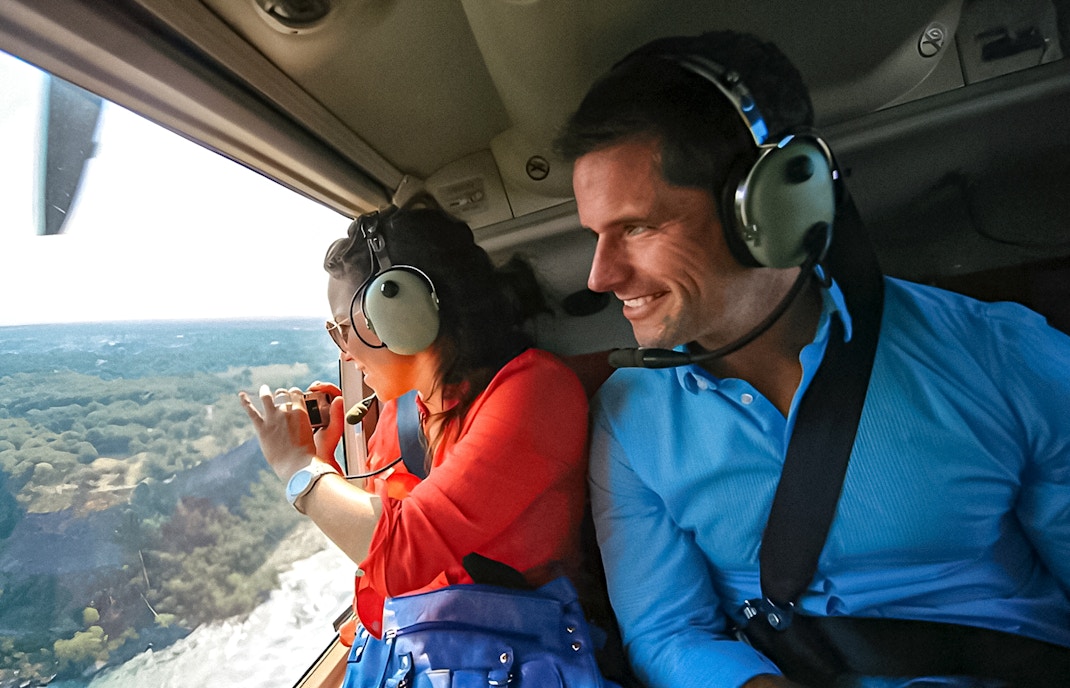 Helicopter passengers view Niagara Falls from above, capturing the scenic landscape.