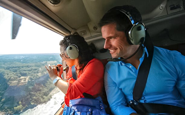 Helicopter passengers view Niagara Falls from above, capturing the scenic landscape.