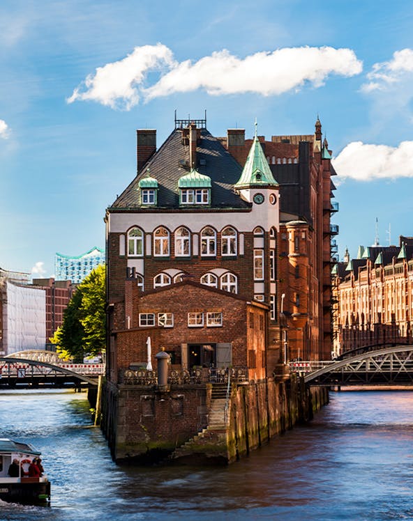 Wasserschloss building in Hamburg's Speicherstadt district with canal and bridges.