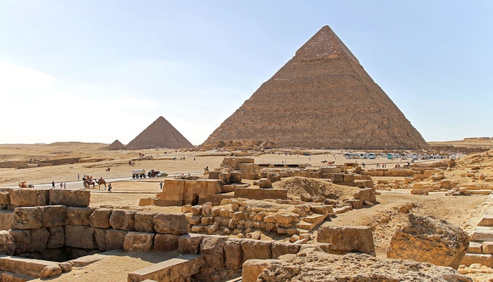 Giza Plateau with pyramids and tourists exploring the ancient site in Egypt.