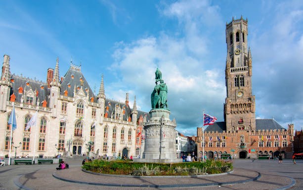 Markt Square in Bruges, Belgium with the Belfry tower and statue in the foreground.