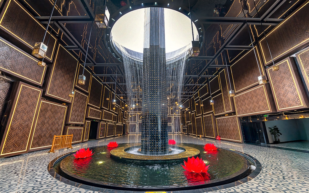 Water feature with red lotus flowers inside Ba Den Mountain tourist area, Tay Ninh, Vietnam.