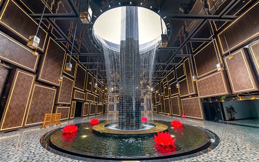 Water feature with red lotus flowers inside Ba Den Mountain tourist area, Tay Ninh, Vietnam.