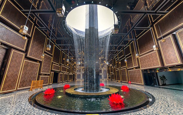 Water feature with red lotus flowers inside Ba Den Mountain tourist area, Tay Ninh, Vietnam.