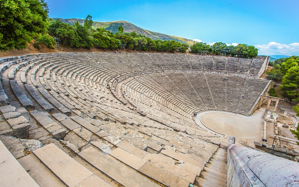 Epidaurus Ancient Theatre with stone seating and stage, surrounded by trees.