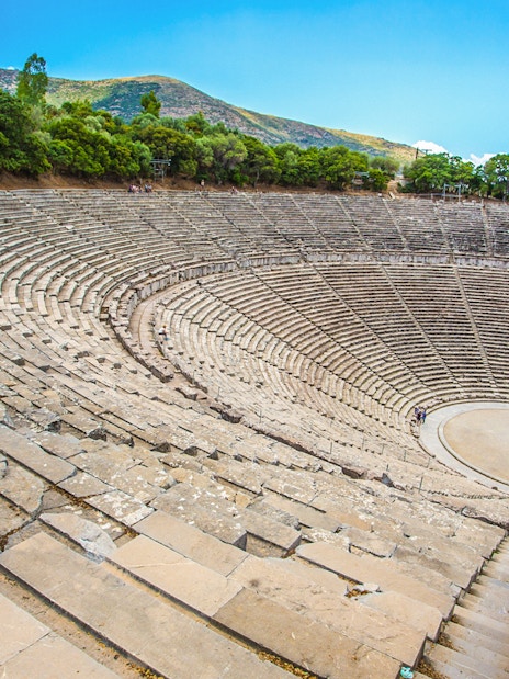 Epidaurus Ancient Theatre with stone seating and stage, surrounded by trees.