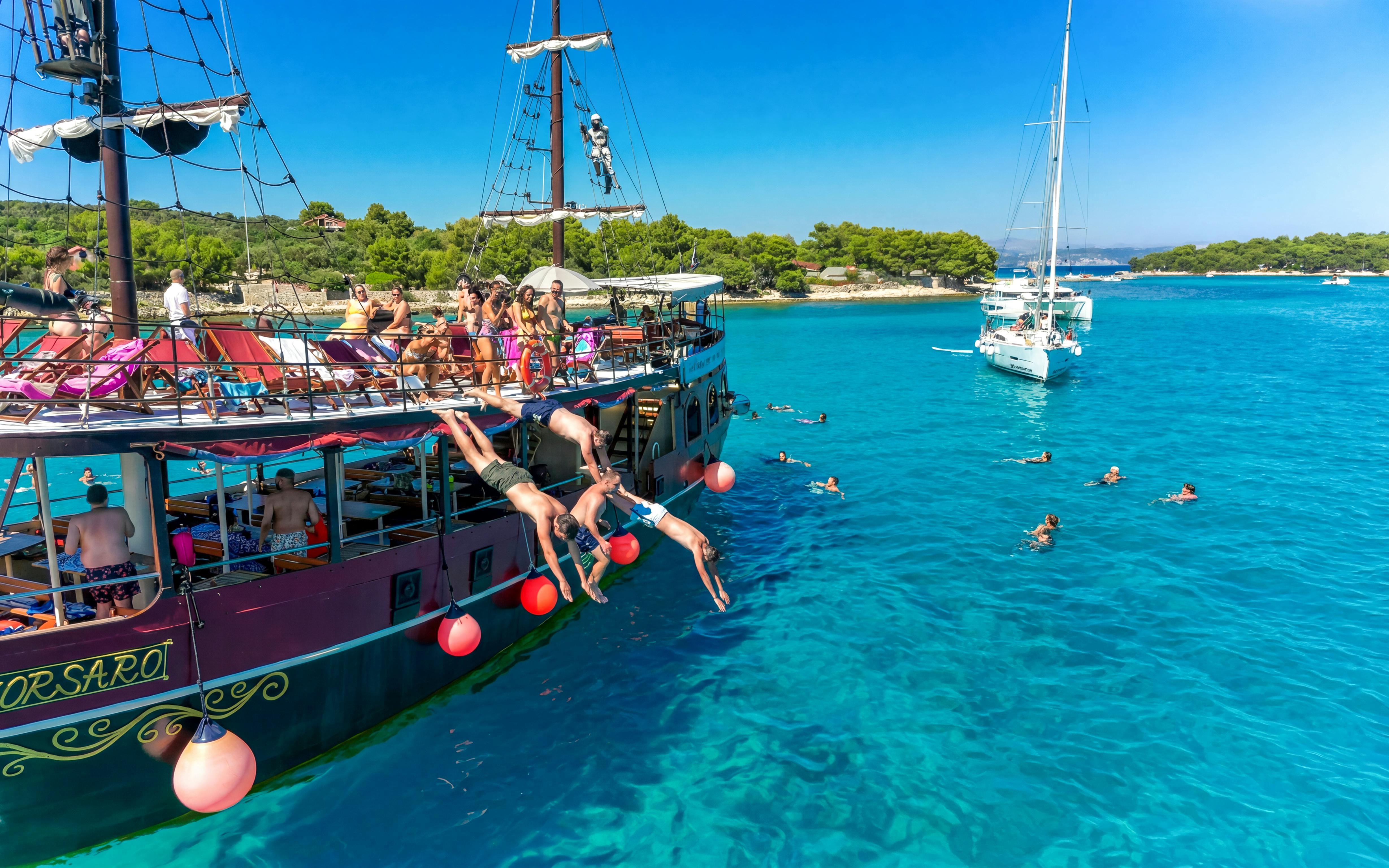 Tourists diving from a boat into clear waters near an exclusive beach resort.