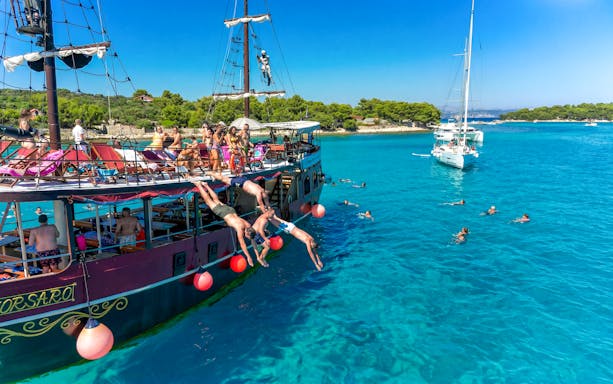 Tourists diving from a boat into clear waters near an exclusive beach resort.