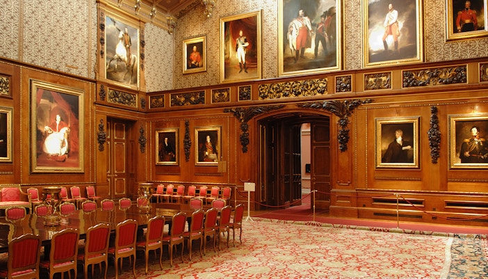 Windsor Castle interior with ornate wood paneling and historical portraits.