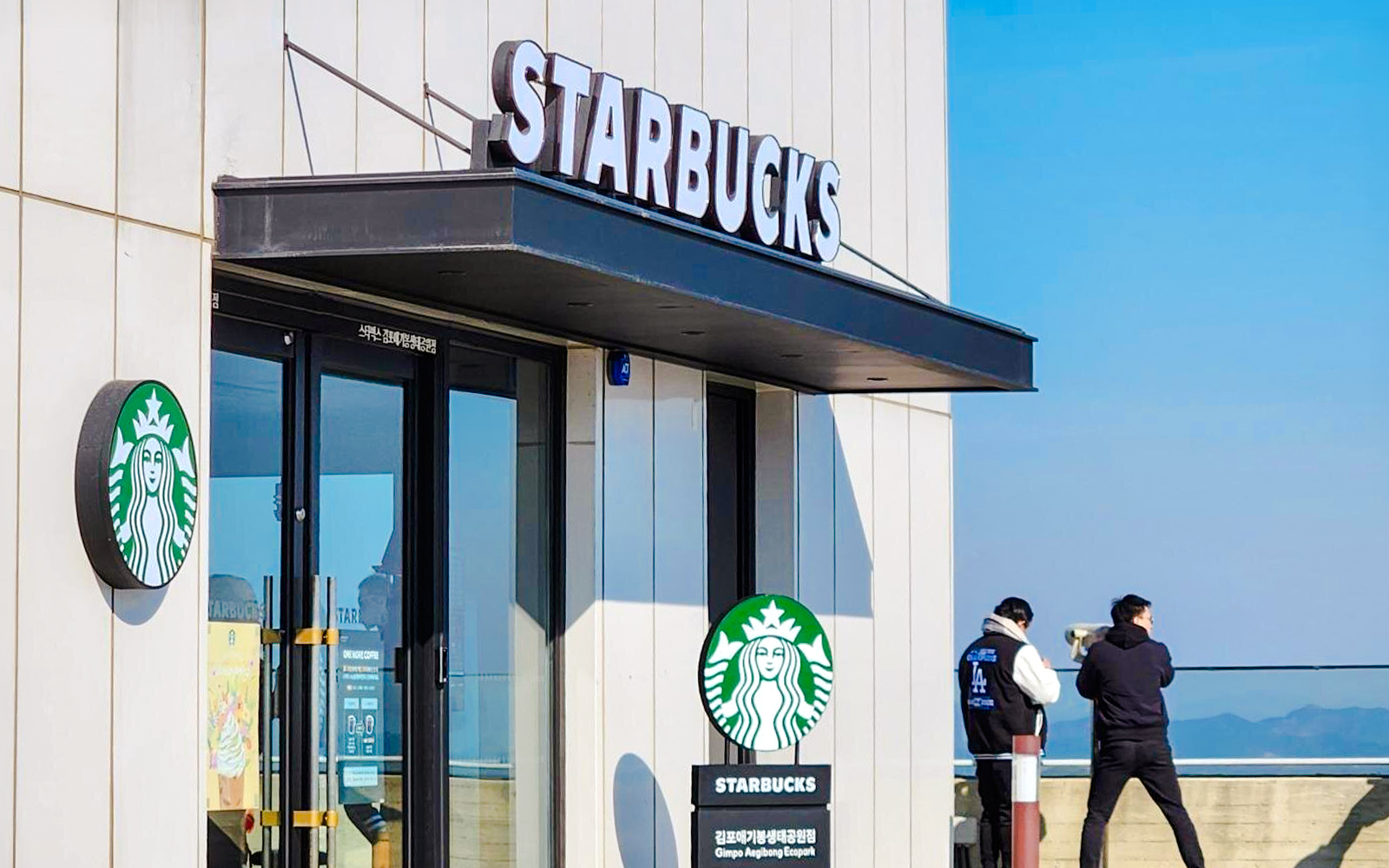Starbucks entrance at Aegibong Observatory, DMZ, South Korea with visitors looking out.