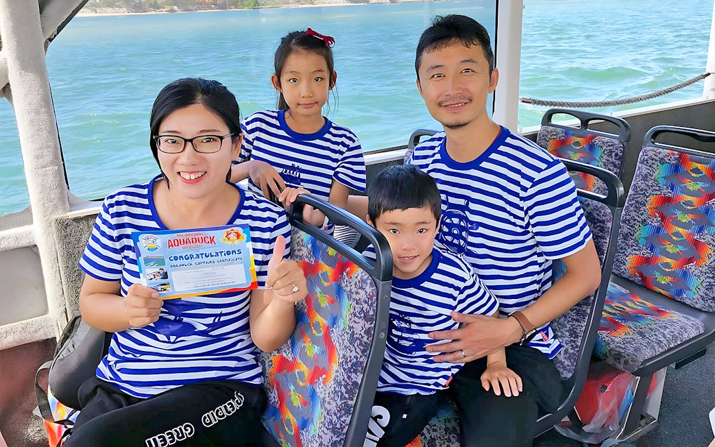 Family on Aquaduck Sunshine Coast tour holding certificate, seated on river cruise boat.