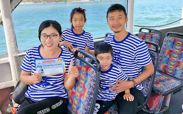 Family on Aquaduck Sunshine Coast tour holding certificate, seated on river cruise boat.