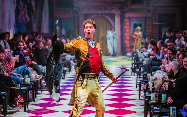 Performer in colorful costume engaging audience at Plied and Prejudice show.