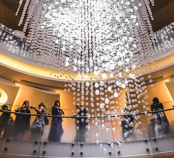 Guests on balcony under chandelier at Dubai Opera.