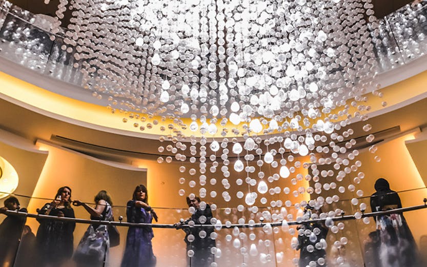 Guests on balcony under chandelier at Dubai Opera.