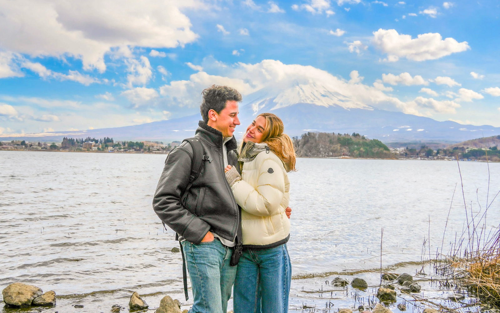 Couple smiling by Lake Ashi with Mount Fuji in the background.