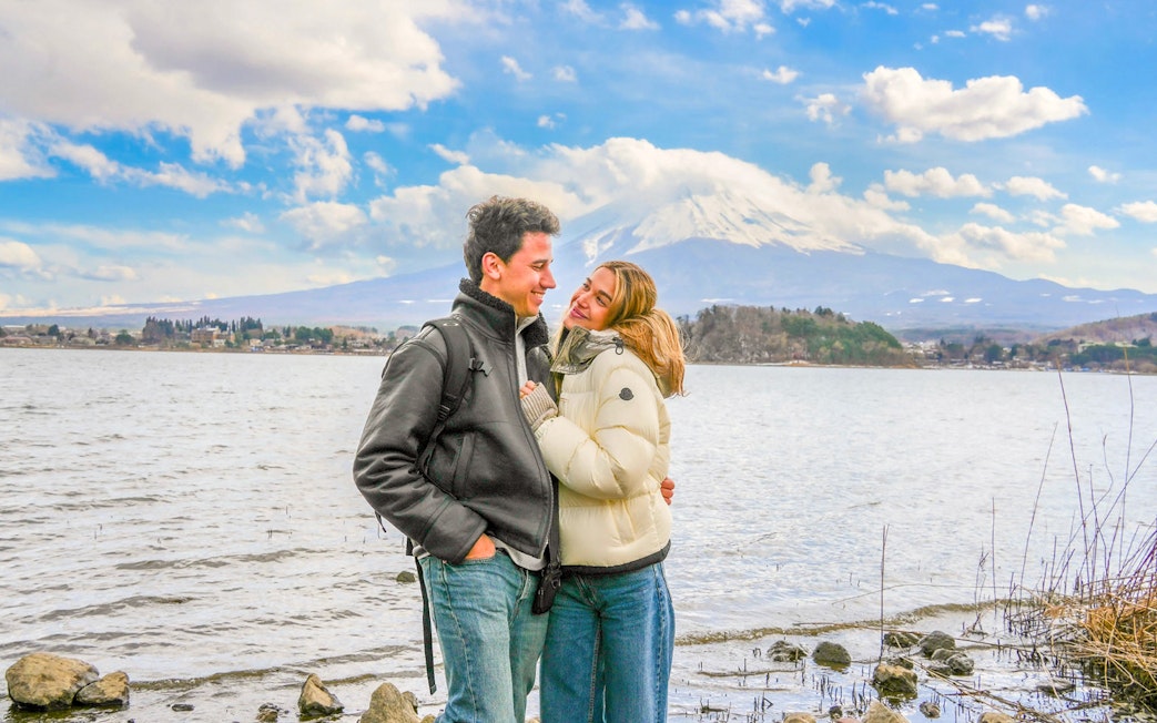 Couple smiling by Lake Ashi with Mount Fuji in the background.