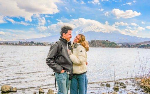 Couple smiling by Lake Ashi with Mount Fuji in the background.