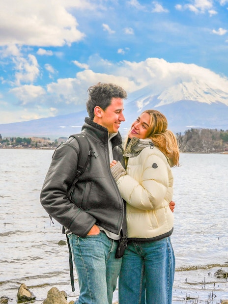 Couple smiling by Lake Ashi with Mount Fuji in the background.