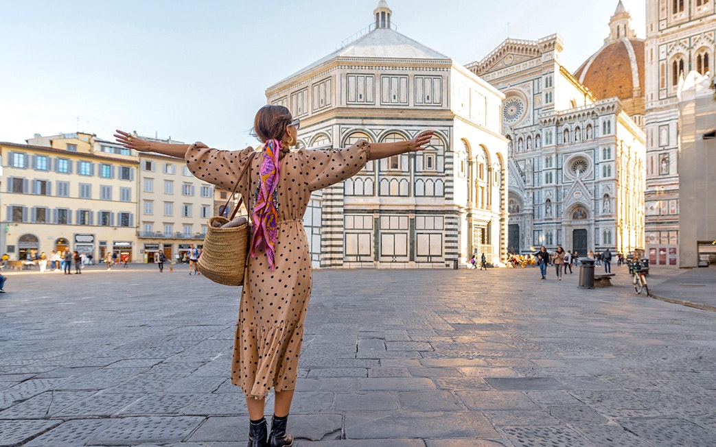Traveler with open arms in front of Florence Cathedral during a city tour.