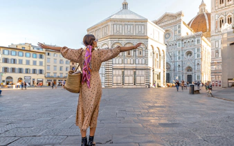 Traveler with open arms in front of Florence Cathedral during a city tour.