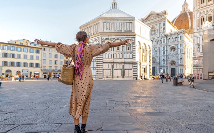 Traveler with open arms in front of Florence Cathedral during a city tour.