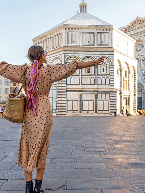 Traveler with open arms in front of Florence Cathedral during a city tour.