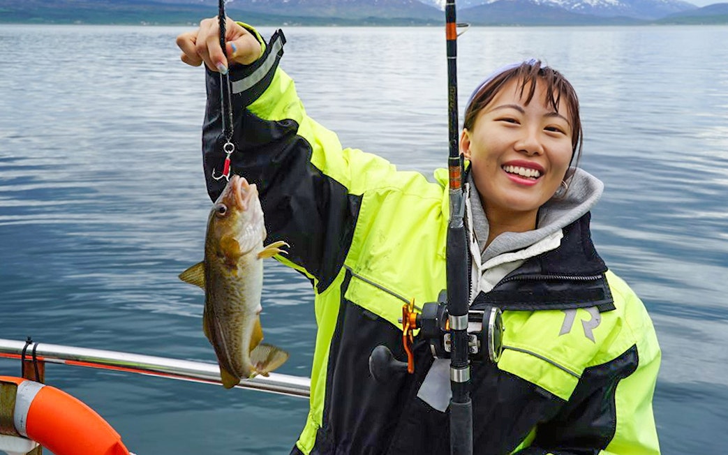 Fishing on a cruise with a catch in hand, scenic ocean backdrop.