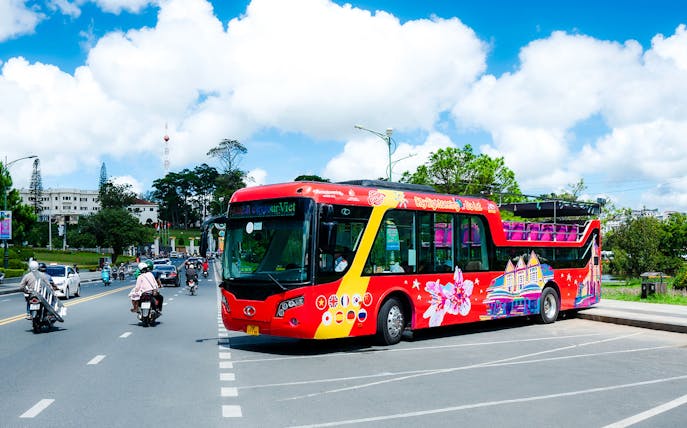 Hop on Hop off bus parked in Da Lat, Vietnam with cityscape in background.