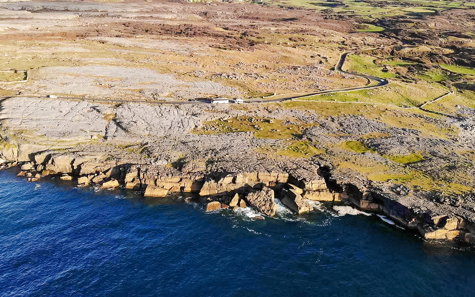Aerial view of rocky coastline on the Aran Islands, Ireland, with cliffs meeting the Atlantic Ocean.