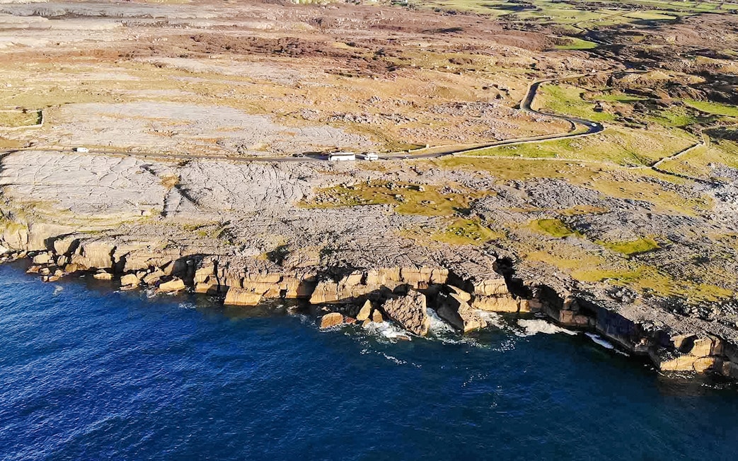 Aerial view of rocky coastline on the Aran Islands, Ireland, with cliffs meeting the Atlantic Ocean.