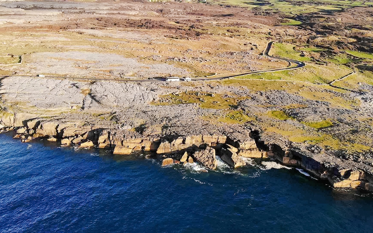 Aerial view of rocky coastline on the Aran Islands, Ireland, with cliffs meeting the Atlantic Ocean.