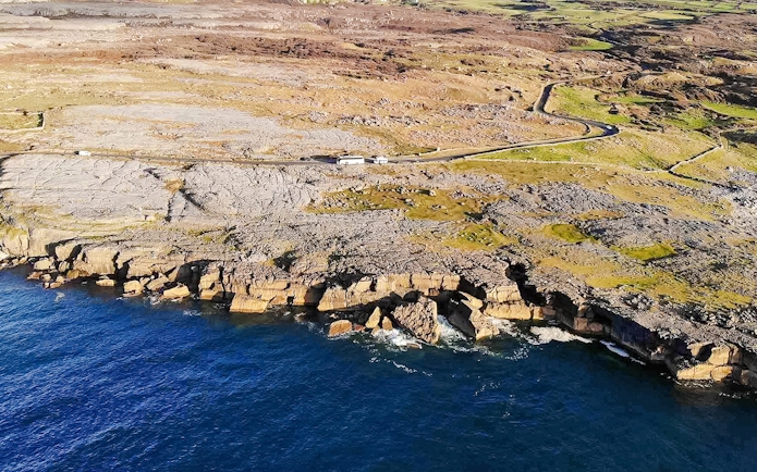 Aerial view of rocky coastline on the Aran Islands, Ireland, with cliffs meeting the Atlantic Ocean.