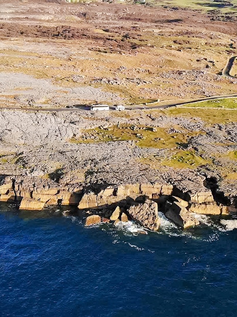 Aerial view of rocky coastline on the Aran Islands, Ireland, with cliffs meeting the Atlantic Ocean.