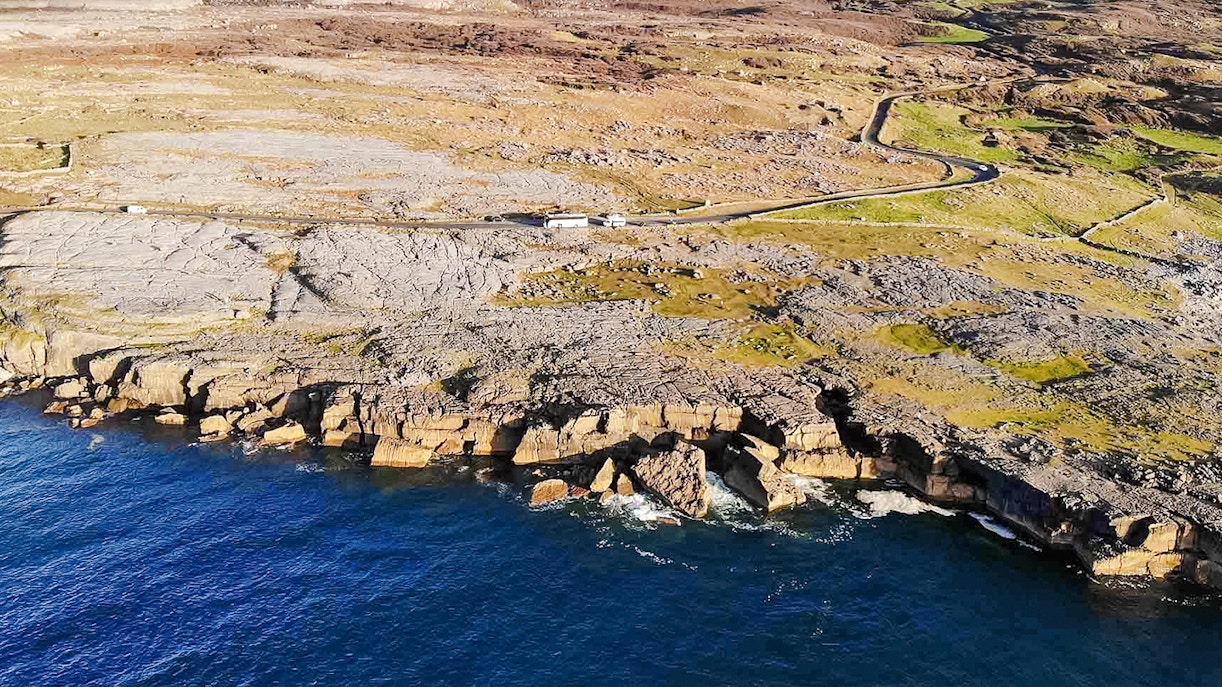 Aerial view of rocky coastline on the Aran Islands, Ireland, with cliffs meeting the Atlantic Ocean.