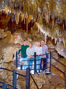 Visitors exploring a cave with stalactites, part of a holiday favorites tour.