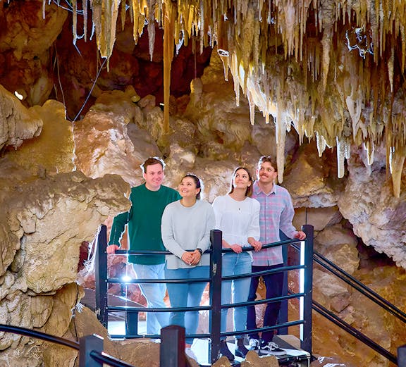 Visitors exploring a cave with stalactites, part of a holiday favorites tour.