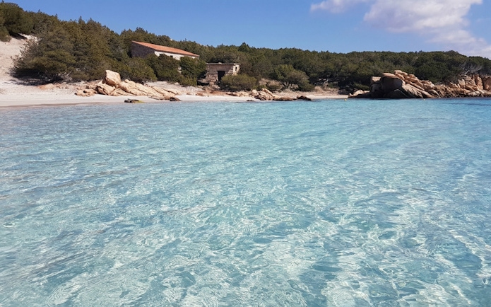 La Maddalena Archipelago beach with clear turquoise water and rocky shoreline.